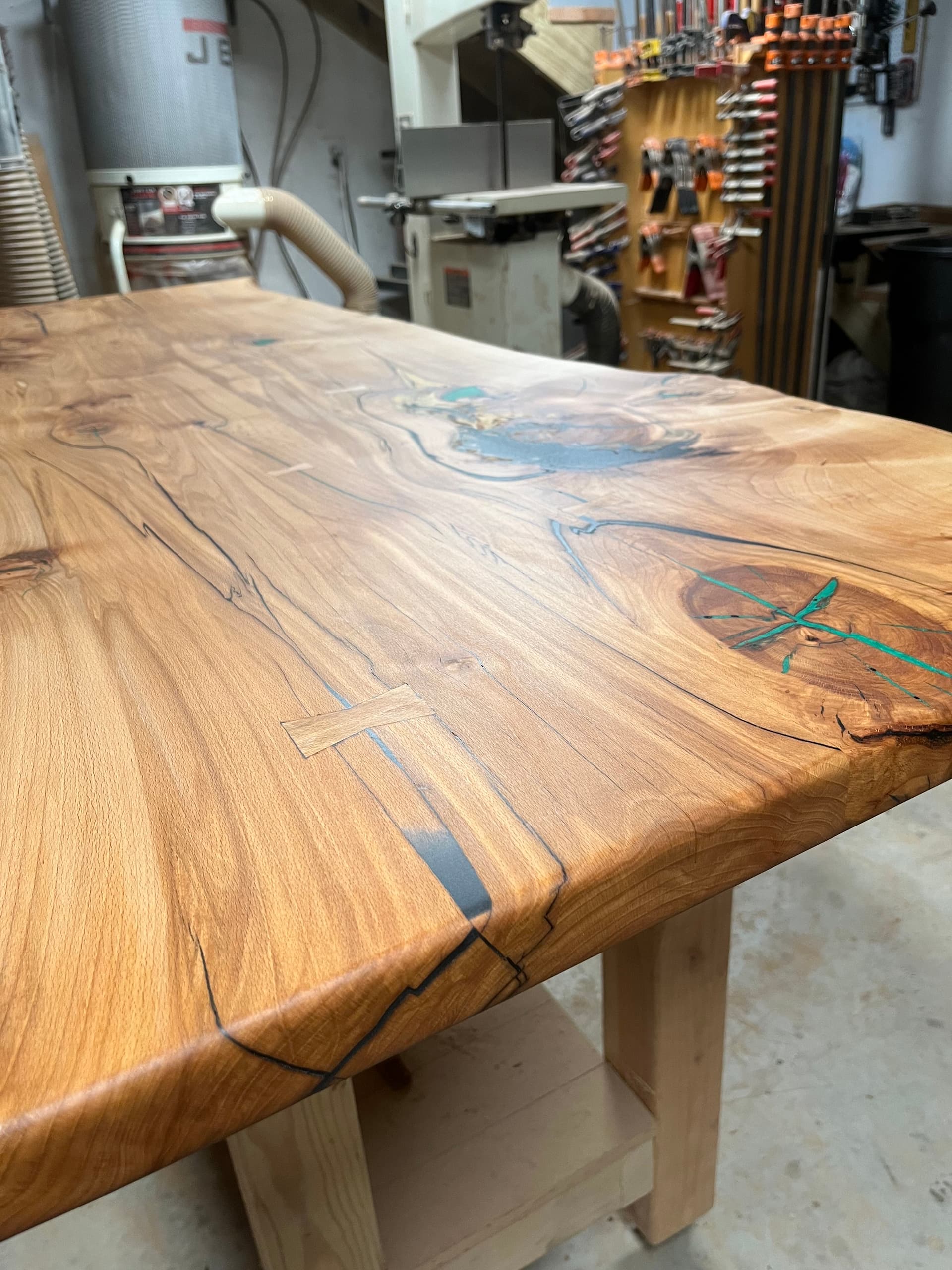 Live edge wood countertop on dark cabinets against a green wall