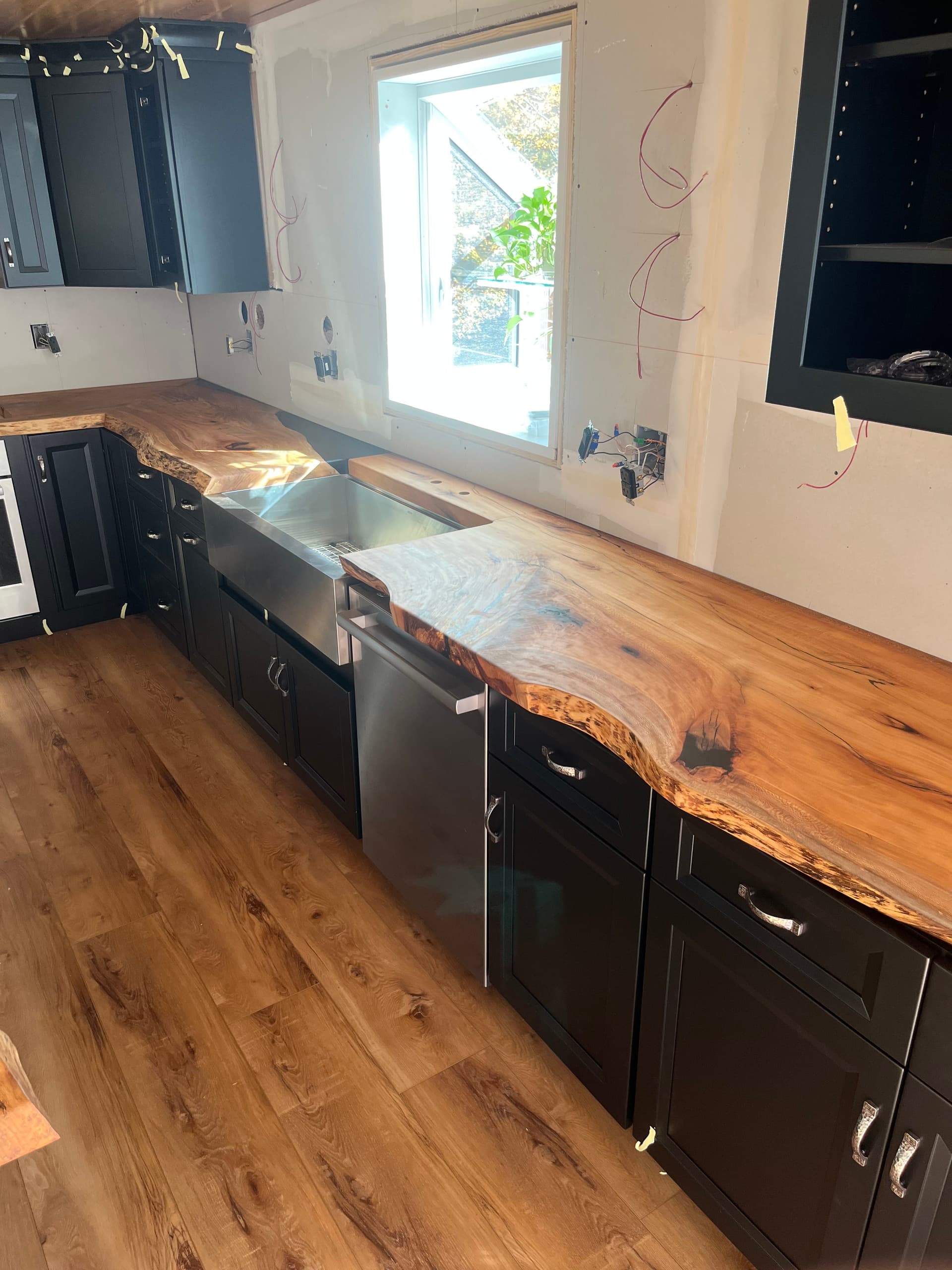 Live edge kitchen countertop being installed over black cabinets